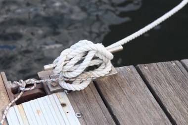 Demirleme kalesi, bir yat iskelesinde bağlama düğümü. Yatın bağlama ipleri diz kapağına bağlı. Halatları bağlamak için iskelede diz çökün. Bağlama ve bağlama ipleri için diz çökün