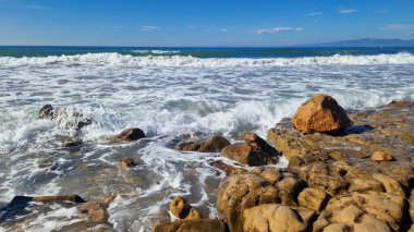 Balear Denizi, Salou, İspanya. Plaj, turkuaz şeffaf deniz, küçük dalgalar. Sahildeki manzara, kayalar. Denizde tatil.