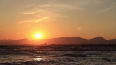 Denizde gün batımı. Balear Denizi, Salou, İspanya. Kumsal, deniz, küçük dalgalar. Sahilde akşam manzarası. Denizde tatil.