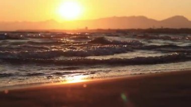 Denizde gün batımı. Balear Denizi, Salou, İspanya. Kumsal, deniz, küçük dalgalar. Sahilde akşam manzarası. Denizde tatil.