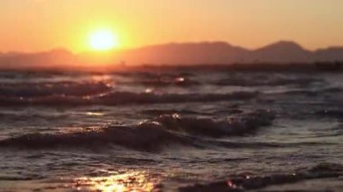 Denizde gün batımı. Balear Denizi, Salou, İspanya. Kumsal, deniz, küçük dalgalar. Sahilde akşam manzarası. Denizde tatil.