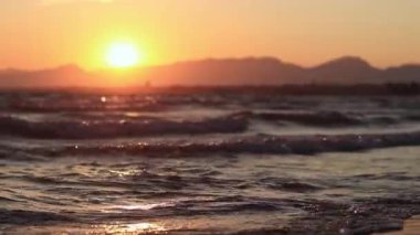 Denizde gün batımı. Balear Denizi, Salou, İspanya. Kumsal, deniz, küçük dalgalar. Sahilde akşam manzarası. Denizde tatil.