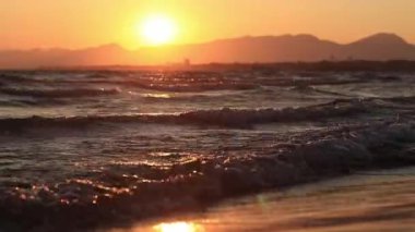Denizde gün batımı. Balear Denizi, Salou, İspanya. Kumsal, deniz, küçük dalgalar. Sahilde akşam manzarası. Denizde tatil.
