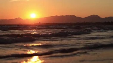 Denizde gün batımı. Balear Denizi, Salou, İspanya. Kumsal, deniz, küçük dalgalar. Sahilde akşam manzarası. Denizde tatil.
