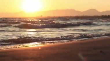 Denizde gün batımı. Balear Denizi, Salou, İspanya. Kumsal, deniz, küçük dalgalar. Sahilde akşam manzarası. Denizde tatil.