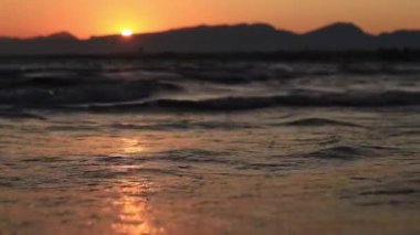 Denizde gün batımı. Balear Denizi, Salou, İspanya. Kumsal, deniz, küçük dalgalar. Sahilde akşam manzarası. Denizde tatil.