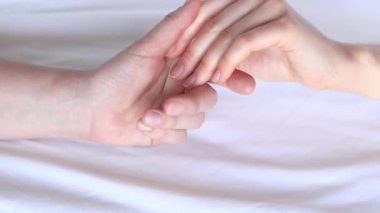 Eşcinsel ilişkiler, lezbiyenler. Beyaz çarşaflar üzerinde birbirine dokunan iki kadın eli. Yatakta iki kadın eli var. Yakın plan. LGBTQ, aşk konsepti