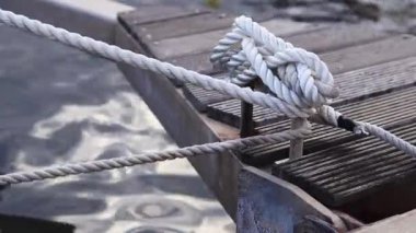 Demirleme kalesi, bir yat iskelesinde bağlama düğümü. Yatın bağlama ipleri diz kapağına bağlı. Halatları bağlamak için iskelede diz çökün. Bağlama ve bağlama ipleri için diz çökün