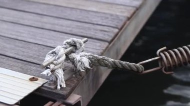 Demirleme kalesi, bir yat iskelesinde bağlama düğümü. Yatın bağlama ipleri diz kapağına bağlı. Halatları bağlamak için iskelede diz çökün. Bağlama ve bağlama ipleri için diz çökün