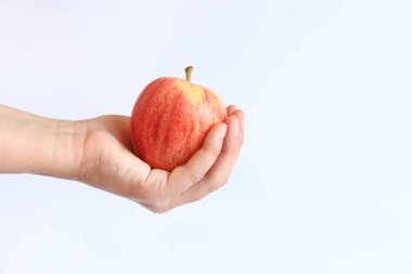 Hafif arka planda bir kadının elinde olgun bir elma. Elmalı bir elin yakın çekimi. Hasat et. Sağlıklı beslenme, vitamin ve diyet kavramı. Meyveler. Beyaz kadın eli bir elma gösteriyor.
