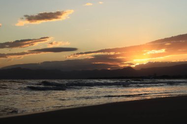 Denizde gün batımı. Balear Denizi, Salou, İspanya. Kumsal, deniz, küçük dalgalar. Sahilde akşam manzarası. Denizde tatil.