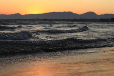 Denizde gün batımı. Balear Denizi, Salou, İspanya. Kumsal, deniz, küçük dalgalar. Sahilde akşam manzarası. Denizde tatil.