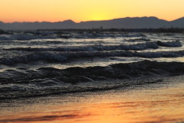 Denizde gün batımı. Balear Denizi, Salou, İspanya. Kumsal, deniz, küçük dalgalar. Sahilde akşam manzarası. Denizde tatil.