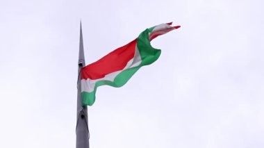Budapeşte, Macaristan - 15 Eylül 2024: Bulutlu bir gökyüzüne yakın çekim Macar bayrağı. Uzun çelik bir bayrak direğinin tepesindeki ana Macar bayrağı. Macar Parlamentosu binasının önündeki bayrak.