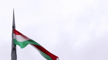 Budapeşte, Macaristan - 15 Eylül 2024: Bulutlu bir gökyüzüne yakın çekim Macar bayrağı. Uzun çelik bir bayrak direğinin tepesindeki ana Macar bayrağı. Macar Parlamentosu binasının önündeki bayrak.