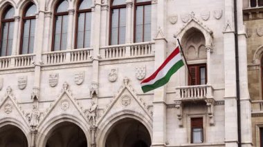 Budapeşte, Macaristan - 15 Eylül 2024: Budapeşte 'deki Macar Parlamentosu binasında Macaristan bayrağı. Budapeşte 'de bayrak direğinde Macar bayrağı dalgalanan parlamento binasının ayrıntıları