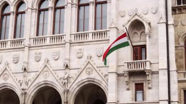 Budapeşte, Macaristan - 15 Eylül 2024: Budapeşte 'deki Macar Parlamentosu binasında Macaristan bayrağı. Budapeşte 'de bayrak direğinde Macar bayrağı dalgalanan parlamento binasının ayrıntıları