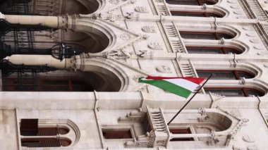 Budapeşte, Macaristan - 15 Eylül 2024: Budapeşte 'deki Macar Parlamentosu binasında Macaristan bayrağı. Budapeşte 'de bayrak direğinde Macar bayrağı dalgalanan parlamento binasının ayrıntıları