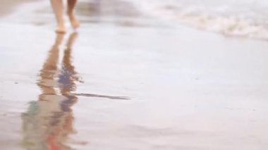 Sahilde kadın bacakları, deniz, yakın plan. Deniz dalgalarının arka planında çıplak ayaklar. Kadın bacakları yakın çekim, plaj tatili. Kumsalda dinlenmek, yaz tatili.