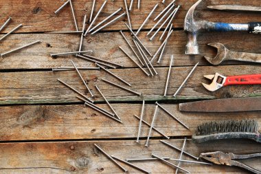 Ahşap bir yüzeyde eski bir el aleti. Ayarlanabilir anahtar, anahtar, balta, çekiç, çivi ve pense. Tamir ve inşaat için aletler, üst manzara. İnşaat geçmişi. Eski paslı bir aletin bileşimi