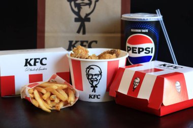 Kyiv, Ukrayna - 20 Ekim 2024: KFC. Striptiz kovası, hamburger, patates kızartması, Pepsi, sos ve kese kağıdı. KFC fast food restoranı. Karanlık bir arka planda fast food. KFC 'de özelleştirilmiş menü ögeleri