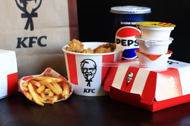 Kyiv, Ukrayna - 20 Ekim 2024: KFC. Striptiz kovası, hamburger, patates kızartması, Pepsi, sos ve kese kağıdı. KFC fast food restoranı. Karanlık bir arka planda fast food. KFC 'de özelleştirilmiş menü ögeleri