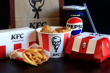 Kyiv, Ukrayna - 20 Ekim 2024: KFC. Striptiz kovası, hamburger, patates kızartması, Pepsi, sos ve kese kağıdı. KFC fast food restoranı. Karanlık bir arka planda fast food. KFC 'de özelleştirilmiş menü ögeleri