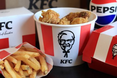 Kyiv, Ukrayna - 20 Ekim 2024: KFC. Striptiz kovası, burger, standart patates kızartması, Peps ve bir kese kağıdı. KFC fast food restoranı. Karanlık bir arka planda fast food. KFC 'de özelleştirilmiş menü ögeleri