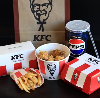 Kyiv, Ukrayna - 20 Ekim 2024: KFC. Striptiz kovası, burger, standart patates kızartması, Peps ve bir kese kağıdı. KFC fast food restoranı. Karanlık bir arka planda fast food. KFC 'de özelleştirilmiş menü ögeleri