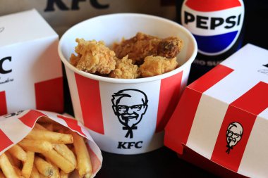 Kyiv, Ukrayna - 20 Ekim 2024: KFC. Striptiz kovası, burger, standart patates kızartması, Peps ve bir kese kağıdı. KFC fast food restoranı. Karanlık bir arka planda fast food. KFC 'de özelleştirilmiş menü ögeleri