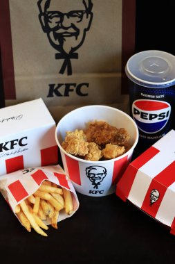 Kyiv, Ukrayna - 20 Ekim 2024: KFC. Striptiz kovası, burger, standart patates kızartması, Peps ve bir kese kağıdı. KFC fast food restoranı. Karanlık bir arka planda fast food. KFC 'de özelleştirilmiş menü ögeleri