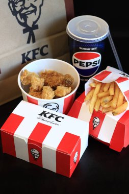 Kyiv, Ukrayna - 20 Ekim 2024: KFC. Striptiz kovası, burger, standart patates kızartması, Peps ve bir kese kağıdı. KFC fast food restoranı. Karanlık bir arka planda fast food. KFC 'de özelleştirilmiş menü ögeleri