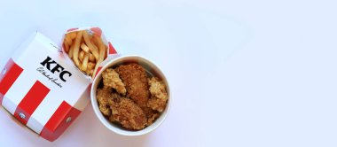 Kyiv, Ukrayna - 20 Ekim 2024: KFC. Şeritli kova, karton kutuda burger ve patates kızartması. KFC fast food restoranı. Fast food hafif arka planda. KFC yiyeceklerinin üst görünümü