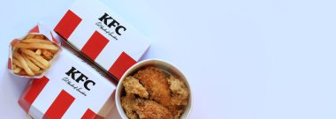 Kyiv, Ukrayna - 20 Ekim 2024: KFC. Şeritli kova, karton kutuda burger ve patates kızartması. KFC fast food restoranı. Fast food hafif arka planda. KFC yiyeceklerinin üst görünümü