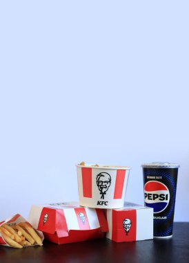 Kyiv, Ukrayna - 20 Ekim 2024: KFC fast food restoranı. Masada hazır yemek, yan görüş. Şeritli kova, karton kutuda hamburger, Pepsi ve patates kızartması. Yiyecek ve içecekler