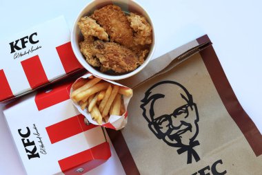 Kyiv, Ukrayna - 20 Ekim 2024: KFC. Şeritli kova, karton kutuda burger ve patates kızartması. KFC fast food restoranı. Fast food hafif arka planda. KFC yiyeceklerinin üst görünümü