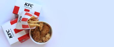 Kyiv, Ukrayna - 20 Ekim 2024: KFC. Şeritli kova, karton kutuda burger ve patates kızartması. KFC fast food restoranı. Fast food hafif arka planda. KFC yiyeceklerinin üst görünümü