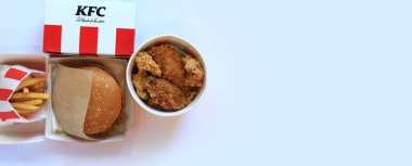 Kyiv, Ukrayna - 20 Ekim 2024: KFC. Şeritli kova, karton kutuda burger ve patates kızartması. KFC fast food restoranı. Fast food hafif arka planda. KFC yiyeceklerinin üst görünümü