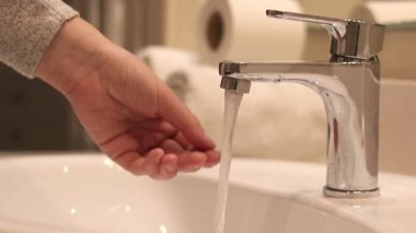 Banyo musluğu, ellerini yıkayan kadın, yakın plan. Banyoda ellerini lavaboda yıkayan bir kadın. Kişisel hijyen. Suyun altında ellerini yıkamak. Sağlık hizmeti konsepti. Ellerini temiz tut.