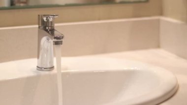 Banyo musluğu, ellerini yıkayan kadın, yakın plan. Banyoda ellerini lavaboda yıkayan bir kadın. Kişisel hijyen. Suyun altında ellerini yıkamak. Sağlık hizmeti konsepti. Ellerini temiz tut.