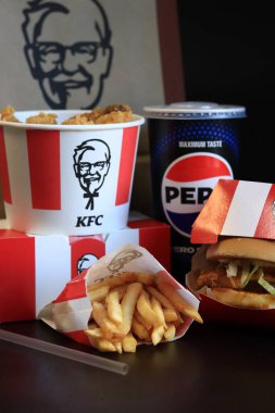 Kyiv, Ukrayna - 20 Ekim 2024: KFC Fast food koyu arka planda. Şeritli kova, hamburger, patates kızartması, Peps ve kese kağıdı. KFC fast food restoranı. KFC 'den lezzetli fast food. Marka logosu