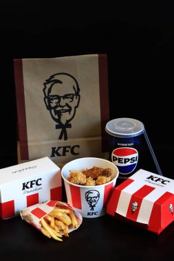 Kyiv, Ukrayna - 20 Ekim 2024: KFC Fast food koyu arka planda. Şeritli kova, hamburger, patates kızartması, Peps ve kese kağıdı. KFC fast food restoranı. KFC 'den lezzetli fast food. Marka logosu