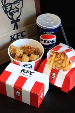 Kyiv, Ukrayna - 20 Ekim 2024: KFC Fast food koyu arka planda. Şeritli kova, hamburger, patates kızartması, Peps ve kese kağıdı. KFC fast food restoranı. KFC 'den lezzetli fast food. Marka logosu