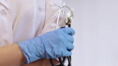 Ellerinde steteskop tutan doktor ya da hemşire. Tıp ve sağlık konsepti. Elinde steteskop olan beyaz önlüklü bir çocuk doktoru. Kadın, tıbbi ve kardiyak izleme cihazı, beyaz arka plan. Tedavi aracı