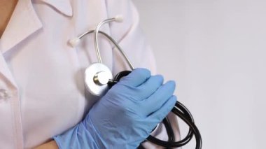 Ellerinde steteskop tutan doktor ya da hemşire. Tıp ve sağlık konsepti. Elinde steteskop olan beyaz önlüklü bir çocuk doktoru. Kadın, tıbbi ve kardiyak izleme cihazı, beyaz arka plan. Tedavi aracı