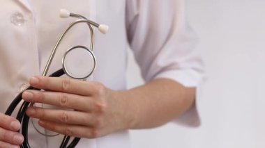 Elinde steteskop olan doktor ya da hemşire. Tıp ve sağlık konsepti. Steteskoplu beyaz önlüklü çocuk doktoru. Kadın, tıbbi ve kardiyak izleme cihazı, beyaz arka plan. Tedavi