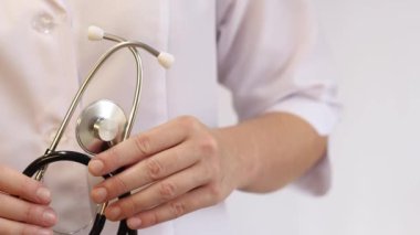Elinde steteskop olan doktor ya da hemşire. Tıp ve sağlık konsepti. Steteskoplu beyaz önlüklü çocuk doktoru. Kadın, tıbbi ve kardiyak izleme cihazı, beyaz arka plan. Tedavi