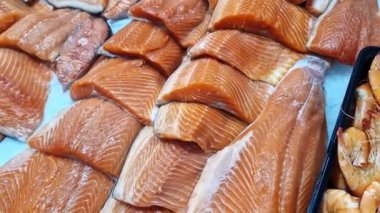 Kırmızı somon ya da alabalık bir mağazada vitrinde satılır. Süpermarketteki balık reyonunda. Lezzetli ve sağlıklı deniz ürünleri. Soğutulmuş balık soğutmalı tezgahın üzerinde yatıyor. Taze balık yakın plan.