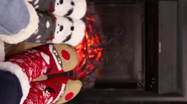Şöminenin yanındaki Noel çoraplı ayak manzaralı ilk kişi. Sıcak Noel çorapları içinde bir çift ayak şöminenin yanında ısınıyor. Noel atmosferi. Kış, Yeni Yıl konsepti