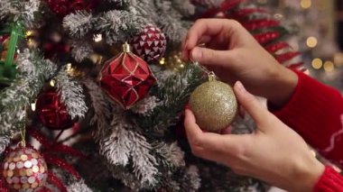 Kadınların elleri ağaca oyuncak asıyor. Yeni yıla hazırlanmak, dekorasyon, Noel ağacı baloları. Bayram kutlaması için kadınların evi hazırlaması. Yeni Yıl ve Noel